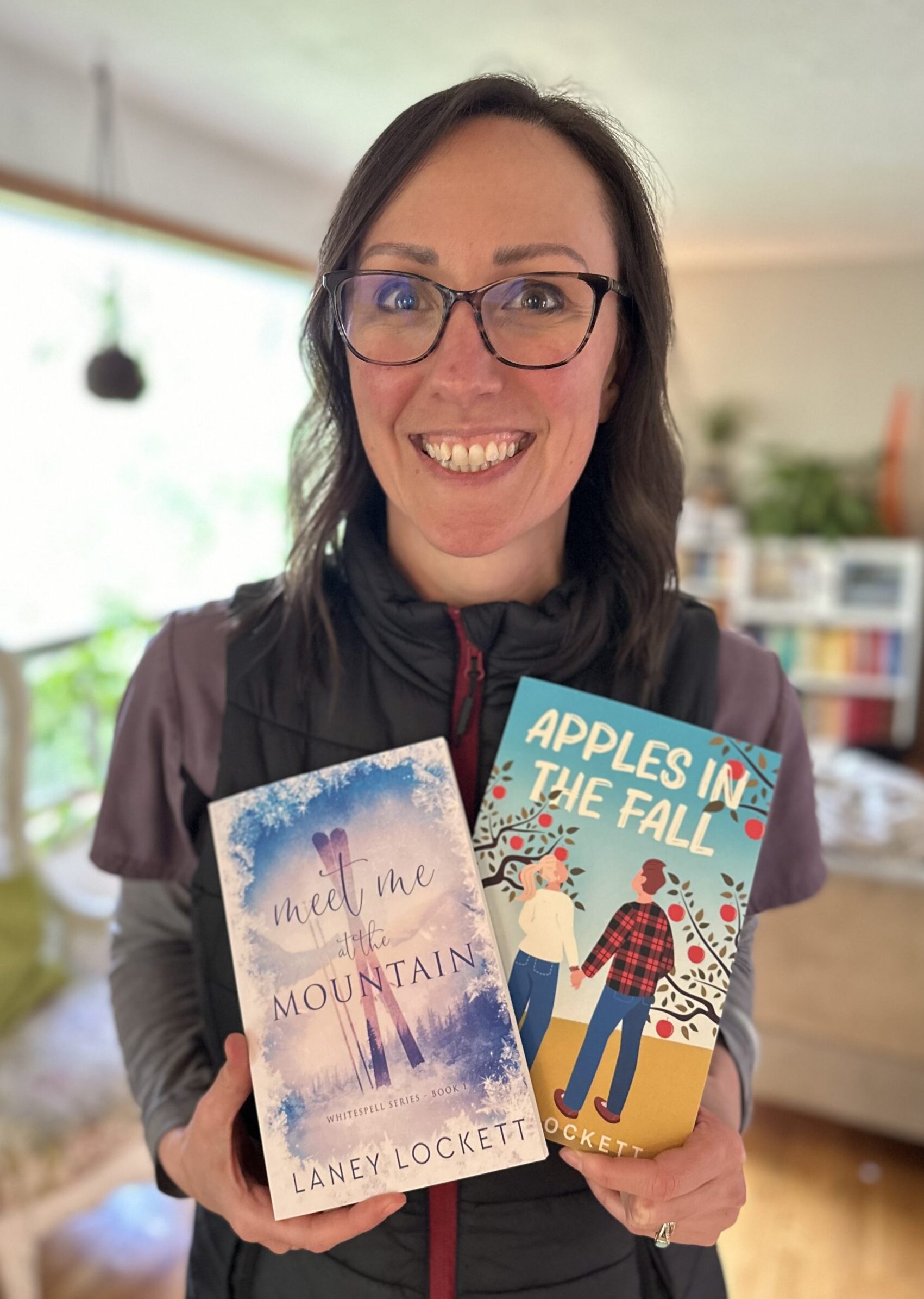 Laney Lockett holding paperback copies of Meet Me at the Mountain and Apples in the Fall. 